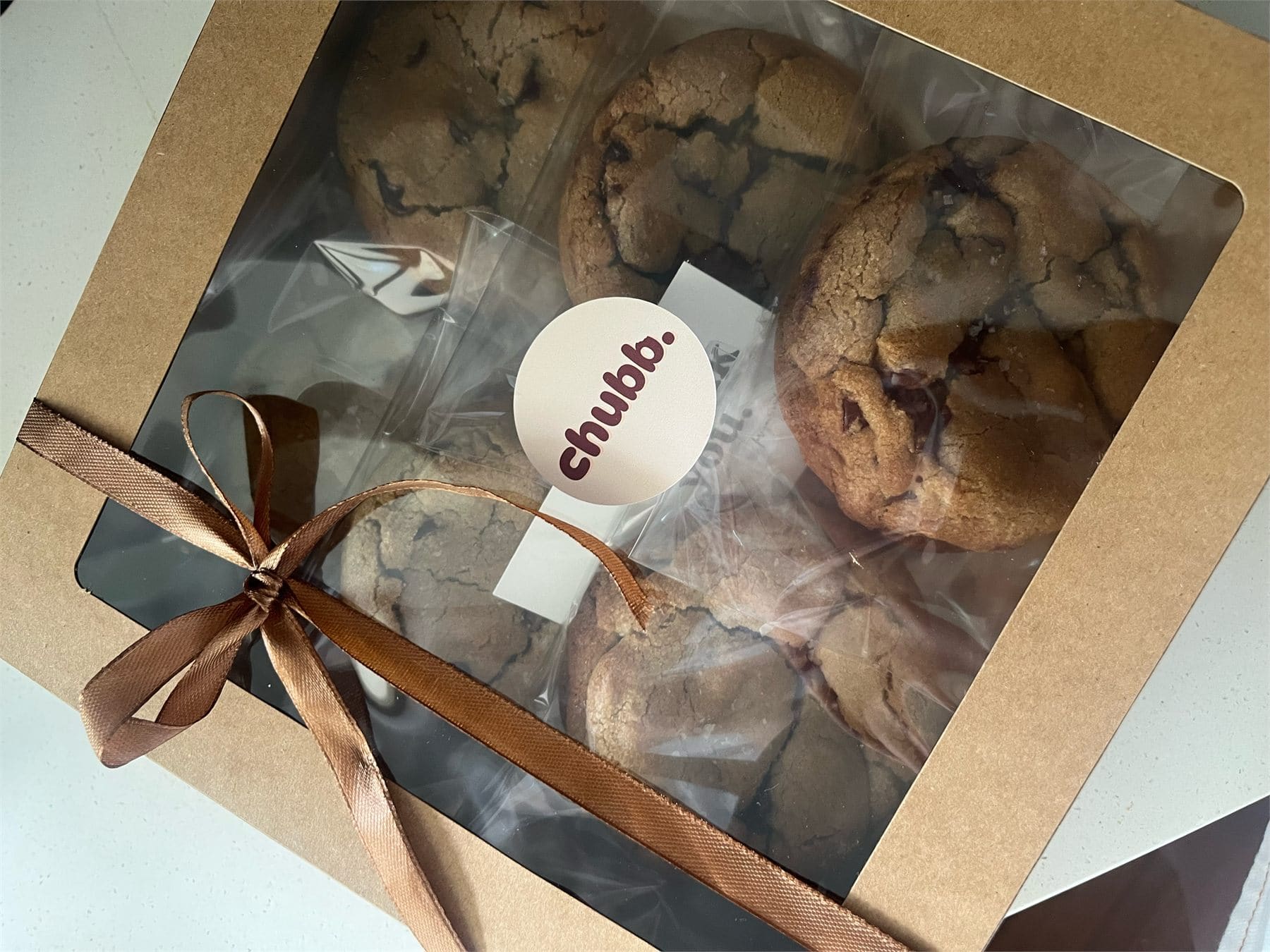 A kraft cookie box tied with a brown satin ribbon and a Chubb sticker