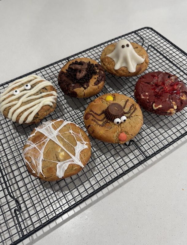 Halloween cookies with ghost and cobweb toppings on a cooling rack